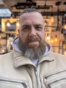 Jens steht in einer dicken Jacke vor ein paar Lampen