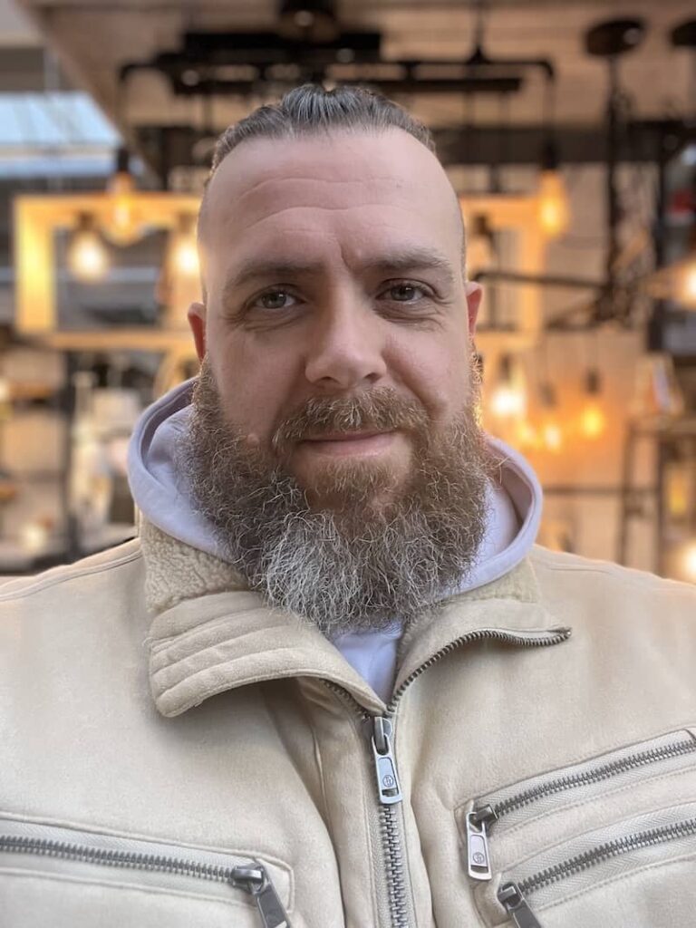 Jens steht in einer dicken Jacke vor ein paar Lampen